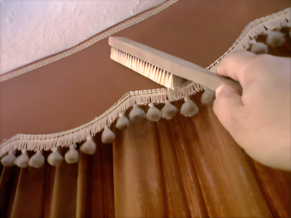 Brushing dust from curtain pelmet during professional curtain cleaning in Exeter